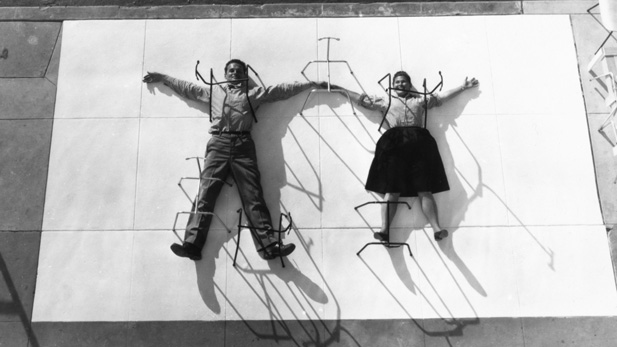 Charles and Ray Eames “pinned” by chair bases, 1947.