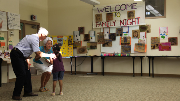 Eddie Islas, Santa Clara Elementary School's principal and reading teacher Lynn Lujan give a certificate of completion to a kindergarten student at the closing ceremony for the San Xavier Summer Reading Program. 