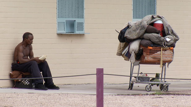 Homeless man reading near Santa Rita park.