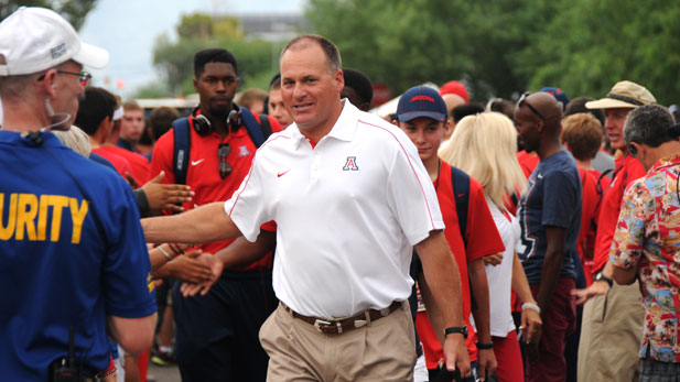 Former University of Arizona football coach Rich Rodriguez greets fans as he leads the team into the stadium, 2012.