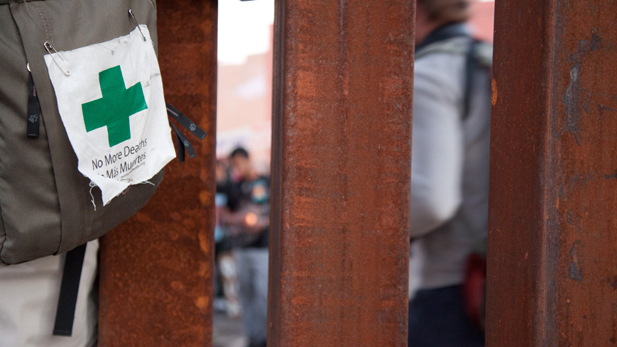 A protestor on the U.S. side of the border fence leans close to talk to protestors on the Mexican side. 