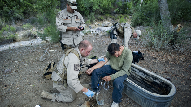 Border Patrol agents help an ailing migrant crosser.