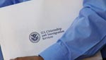 A new US citizen hold his US Citizenship and Immigration packet in his hands.