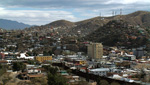 The border of Nogales, Arizona and Nogales, Mexico is separated by a large brown metal fence.