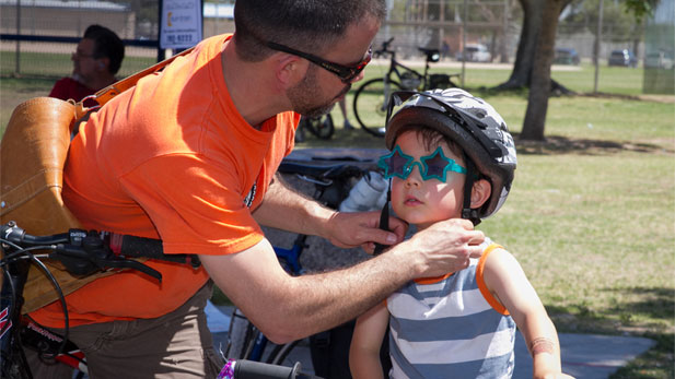A father and his child gear up for bike safety and to enjoy the events of Cyclovia Tucson.