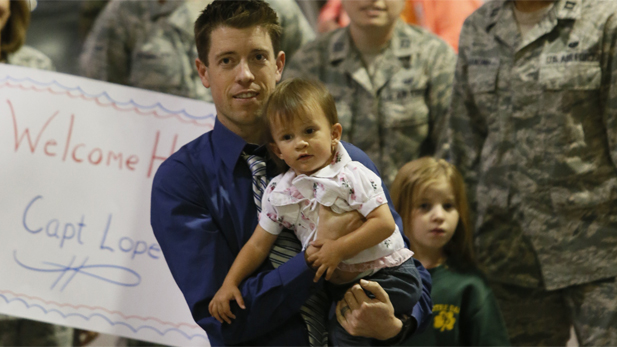 Chris Phelan, with his daughter River, prepares to greet his wife, Star Lopez, upon her arrival home from serving in Afghanistan.