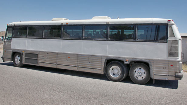 Children who migrated alone to U.S. wave goodbye from inside a bus leaving the Border Patrol facility in Nogales