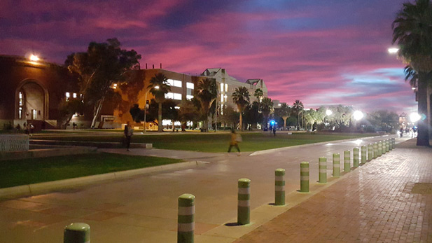 Students walk across the UA Mall as the sun sets in the background. Photo taken December 10th, 2015.