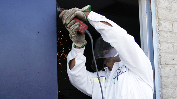 Flores welds a door hinge at Flowing Wells High School. He began at the district on the grounds crew and now heads the welding shop. 