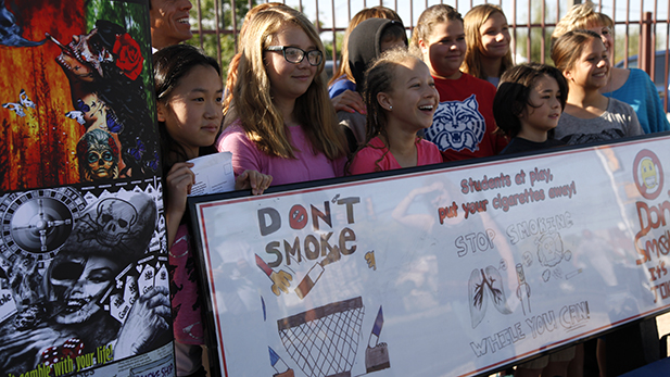 Students from Miles Exploratory Learning Center celebrate the unveiling of smoke-free themed art on a bus bench near their school on March 31, 2015.