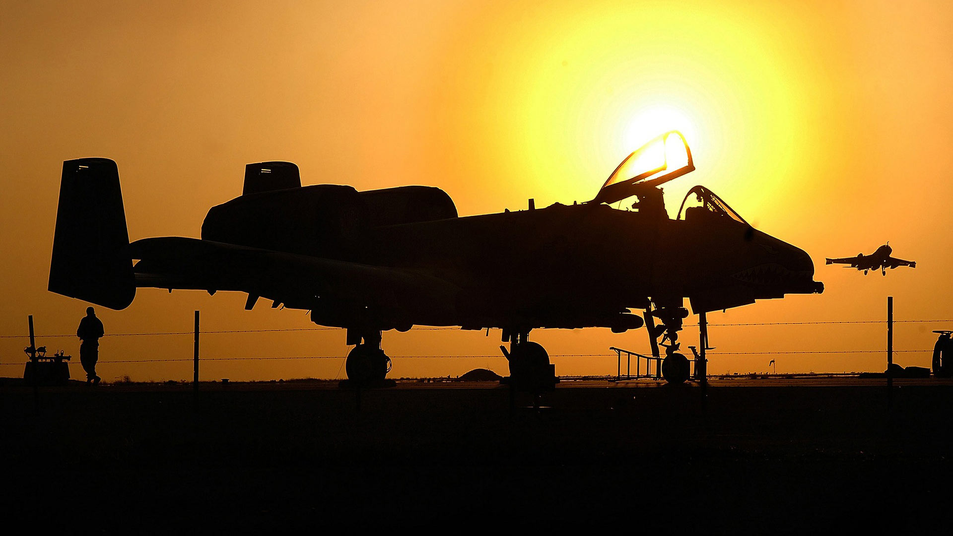 An A-10 aircraft silhouetted by the setting sun.