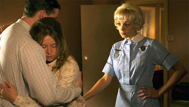 June Dillen (Genevieve Barr) and Kevin Dillen (Tom Christian) hugging as Trixie (Helen George) looks on.