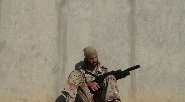 Image of Matt with gun by concrete wall.