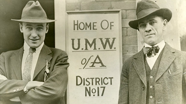 Frank Keeney and Fred Mooney pose next to a UMWA sign in Charleston, WV (1915).