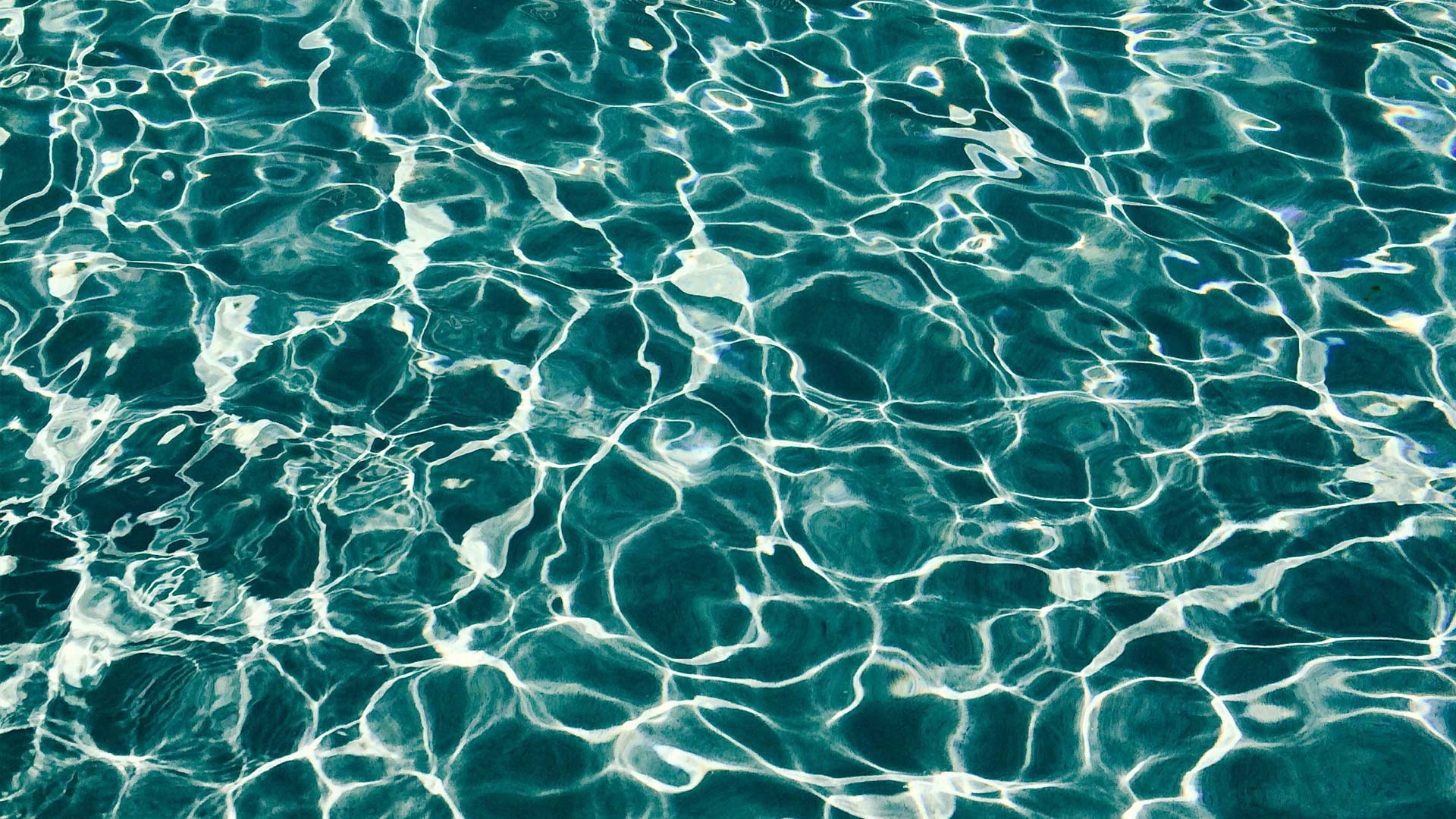 Sunlight reflects off of the water in a swimming pool.