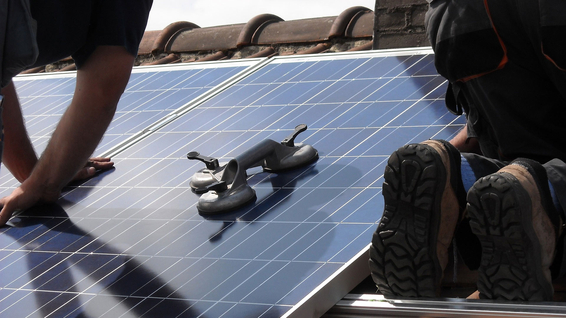 Workers install solar panels on a rooftop.