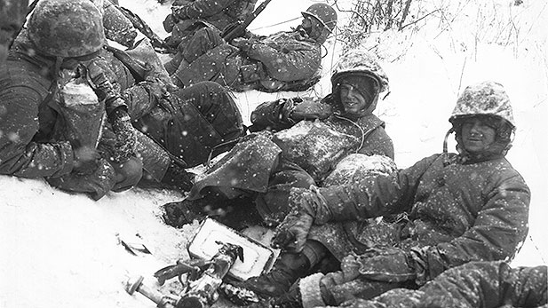 Men of a U.S. Marine mortar squad rest at the side of a snowy road during their withdrawal from the Chosin Reservoir, North Korea. (Dec. 8th, 1950