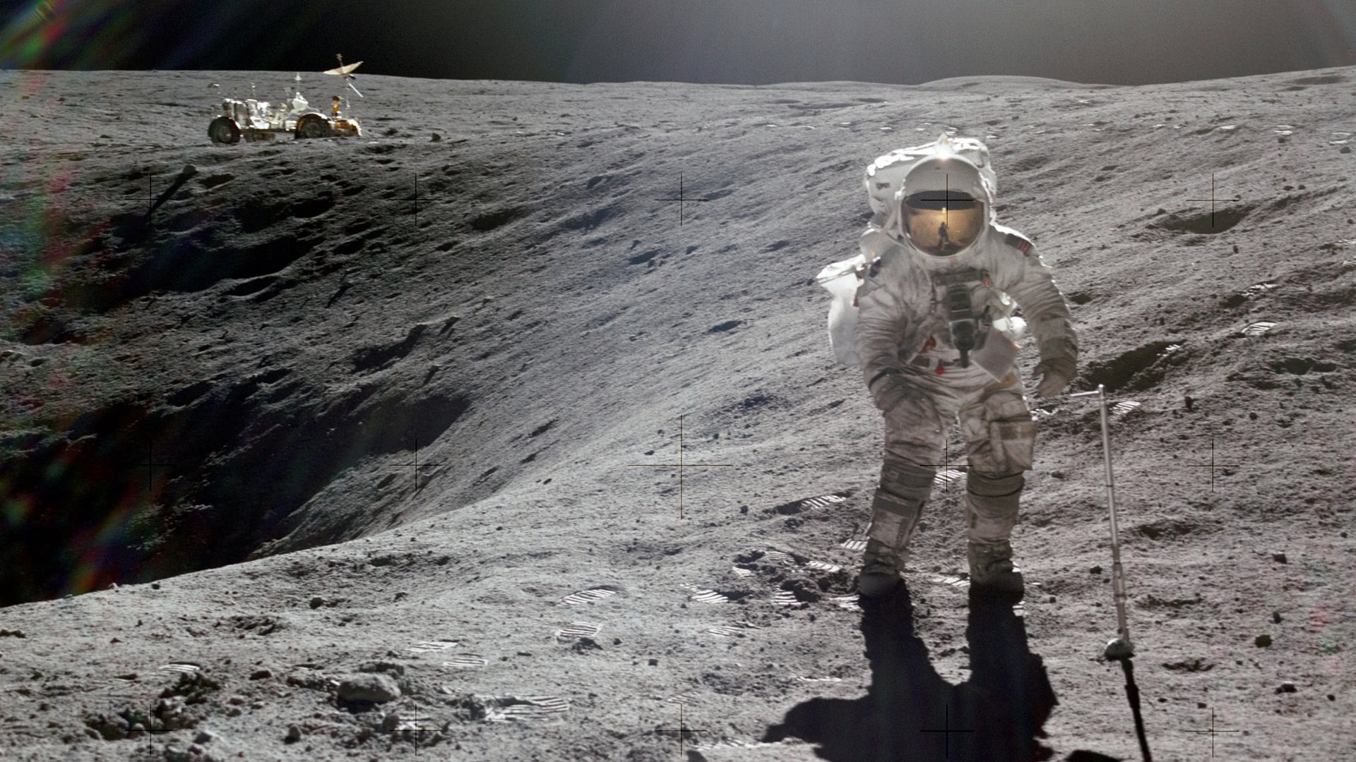 Astronaut Charles M. Duke Jr., lunar module pilot of the Apollo 16 lunar landing mission, is photographed collecting lunar samples at Station no. 1 during the first Apollo 16 extravehicular activity at the Descartes landing site. This picture, looking eastward, was taken by Astronaut John W. Young, commander. Duke is standing at the rim of Plum crater, which is 40 meters in diameter and 10 meters deep. The parked Lunar Roving Vehicle can be seen in the left background.