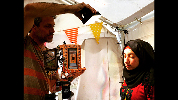 Wayne using his "Us and Them" camera to take a portrait of a refugee in Lesvos Greece