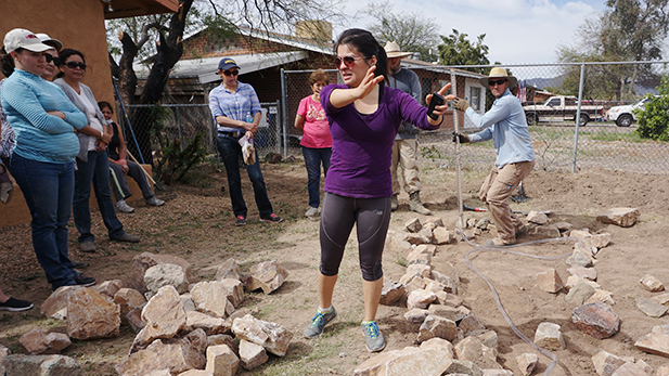 Flor Morales leads a group of women in installing a passive rainwater harvesting system. The experiment is taking place in her yard. 