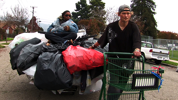 Jason Witt (right) hauls a shopping cart with his girlfriend, Heather Holloman (left), on top.