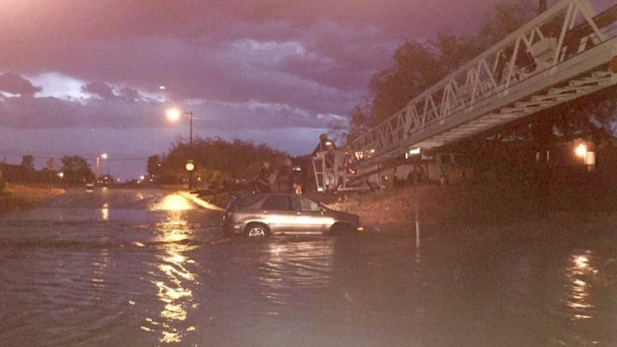 Tucson firefighters pull four people from a car swept downstream near East Lee Street and North 9th Avenue in Sunday's rainstorm.