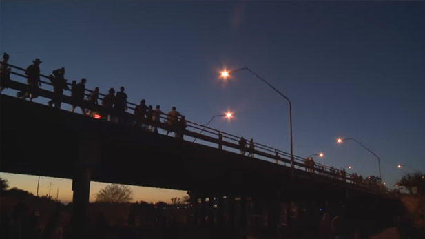 Pedestrians look over the edge of an overpass at Rillito River Park.