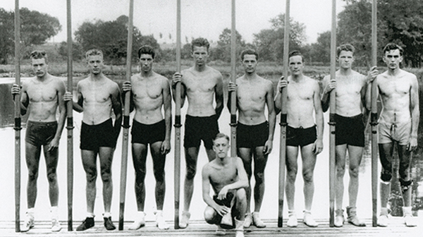 The 1936 University of Washington’s varsity crew team. Left to right standing: Don Hume, Stroke; Joe Rantz, 7; George Hunt, 6; Jim McMillin, 5; John White, 4; Gordon Adams, 3; Charles Day, 2; and Roger Morris, 1. Kneeling: Bob Moch, Coxwain