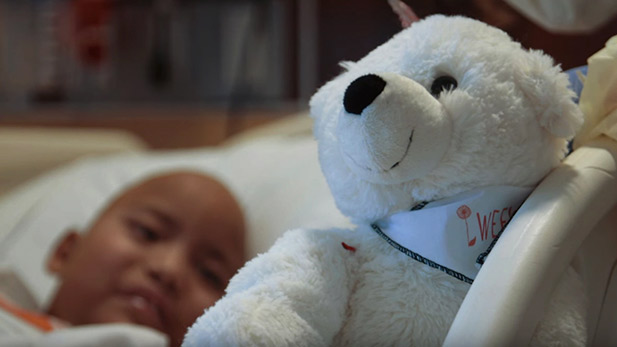 A young hospital patient looks on at their teddy bear.