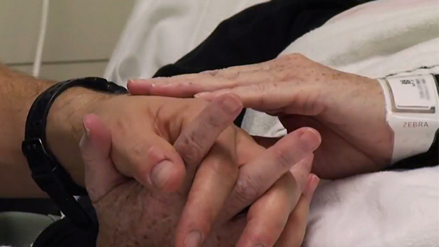 A hospital patient is comforted by holding hands.