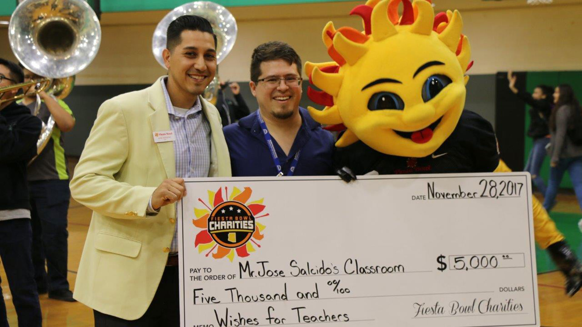 Fiesta Bowl representative José Moreno presents the check to teacher José Salcido with "Spirit," the Fiesta Bowl mascot. 