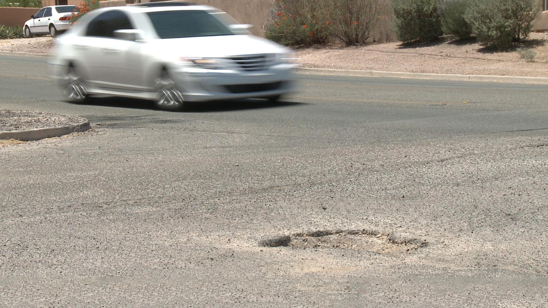 A car travels near a pothole on a Tucson-area street.