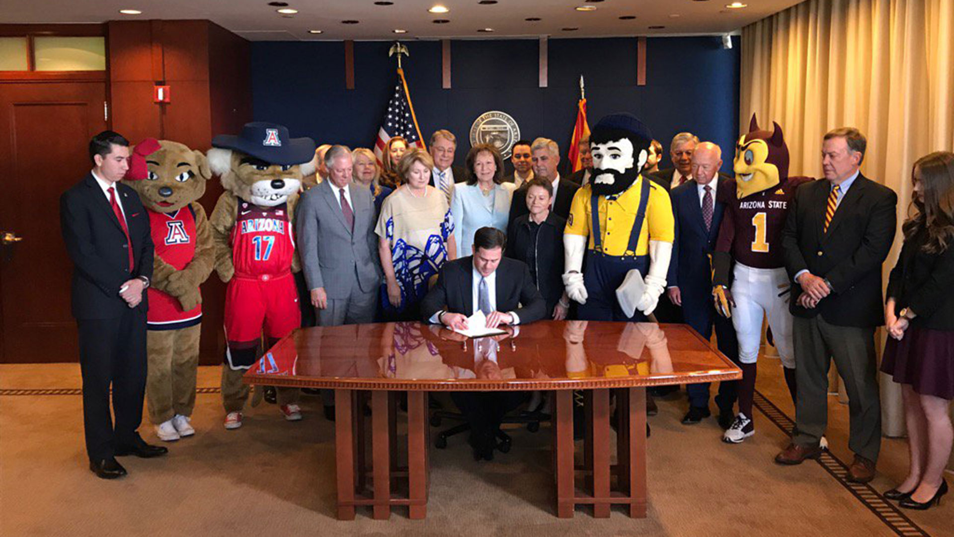 Arizona Gov. Doug Ducey, accompanied by Arizona regents, university officials and others, signs a plan to create a borrowing package to fund university maintenance, May 22, 2017.