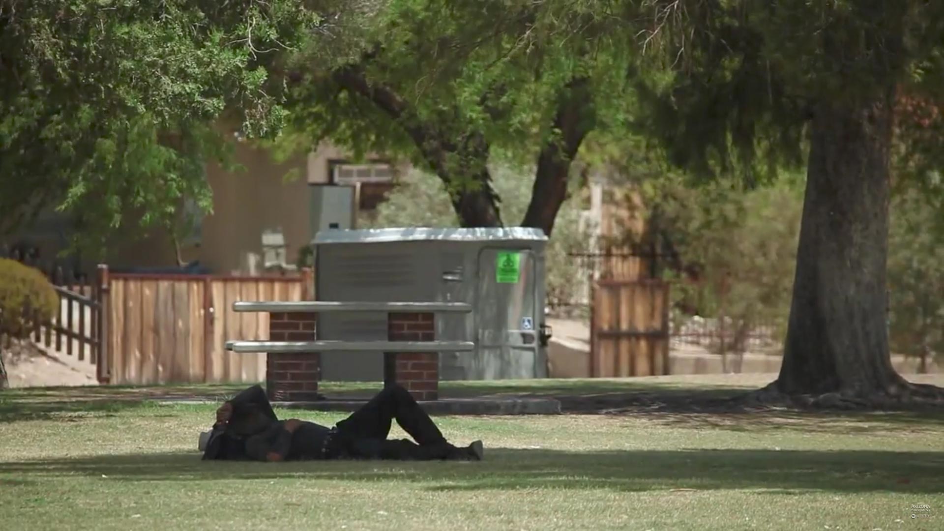 A man rests in the shade on a hot day in Tucson.