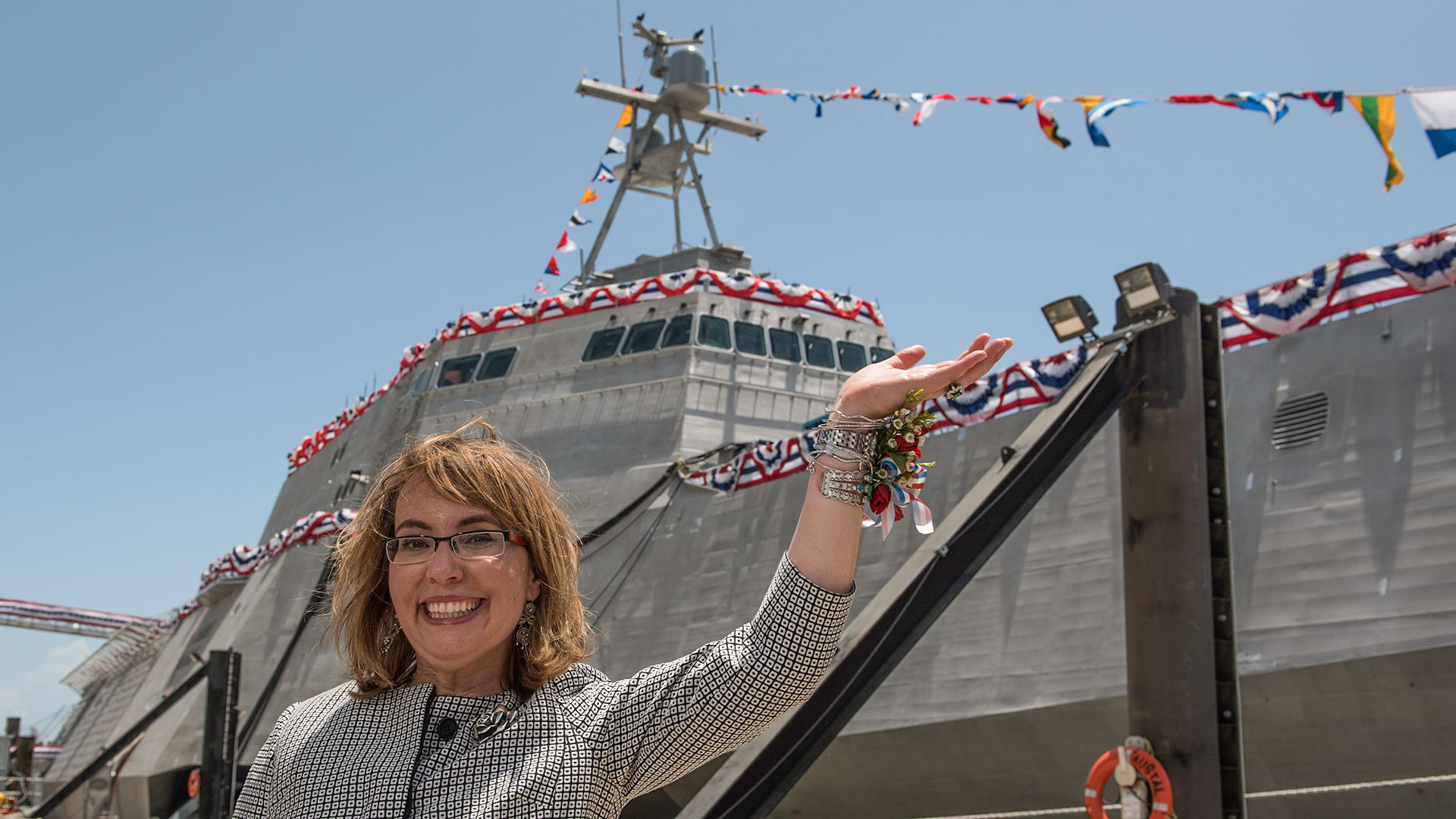 Former U.S. Rep. Gabrielle "Gabby" Giffords waves to a crowd in front of the littoral combat ship, USS Gabrielle Giffords (LCS 10), named for her. Giffords was on the stage as Dr. Jill Biden christened the ship at Austal USA in Mobile, Ala. The 419-foot ship was built at the Austal shipyard and is the Navy's 10th littoral combat ship designed to operate in shallow waters near the coast. It is 16th U.S. naval ship to be named for a woman and only the 13th since 1850 to be named for a living person. June 13, 2015