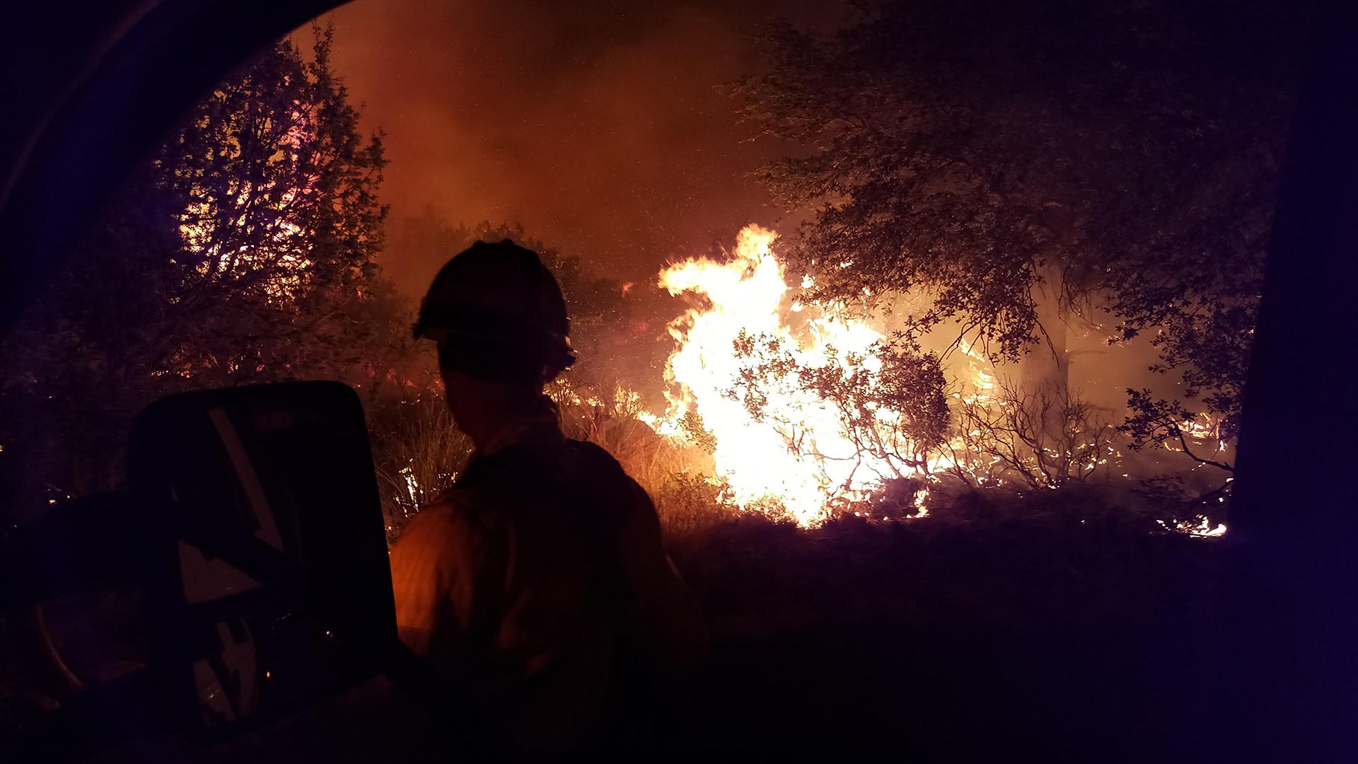 Looking through a window of a truck at a firefighter watching the Burro Fire.