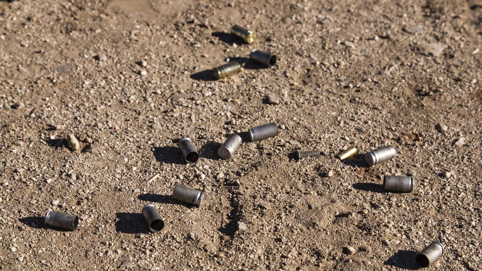 Bullet casings on ground at an outdoor firing range.