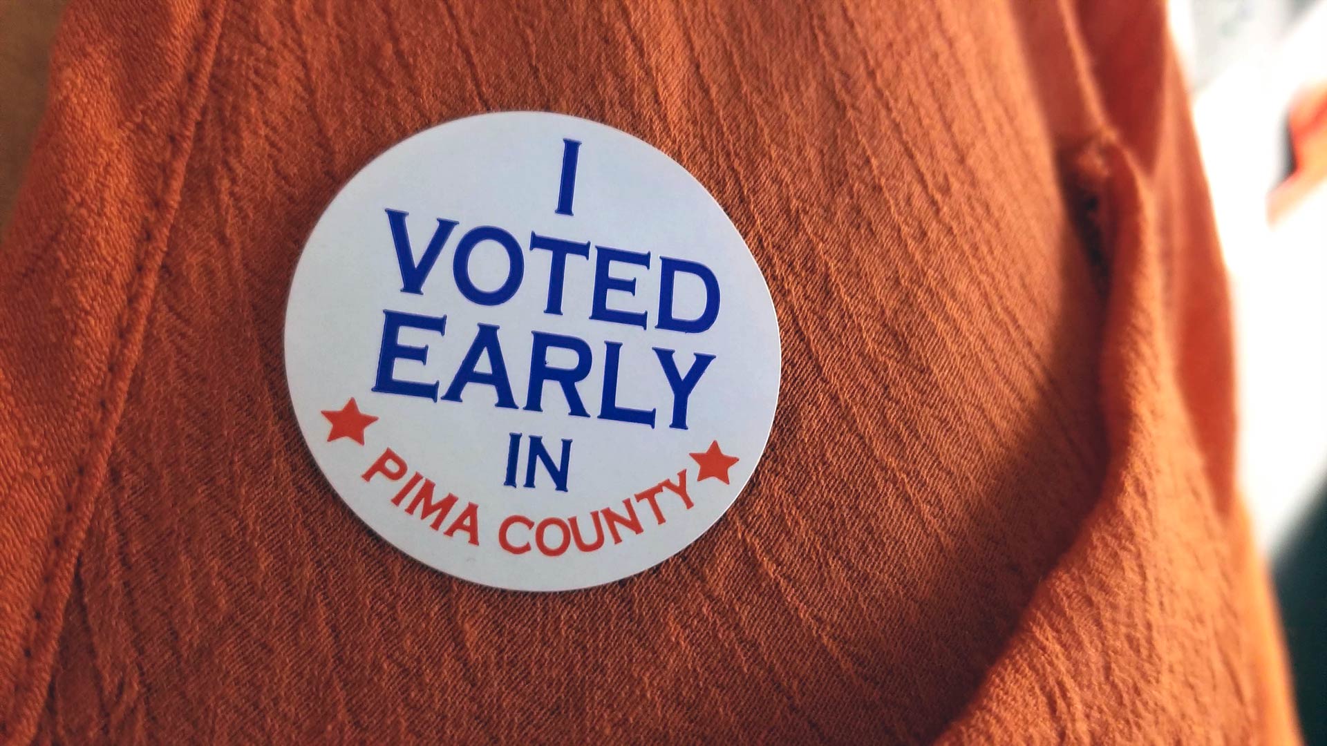 A voter displays their "I Voted Early in Pima County" sticker.