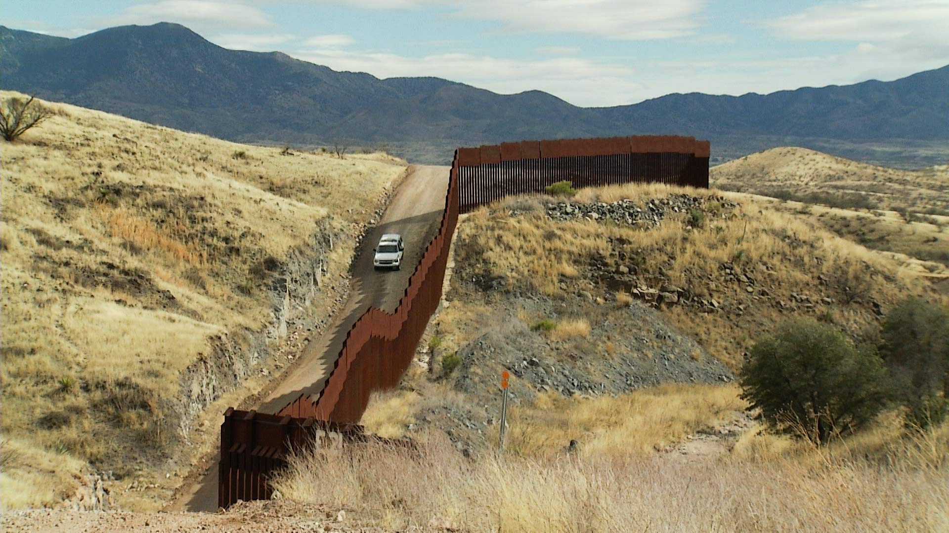 A Border Patrol vehicle travels along a stretch of fence along the U.S.-Mexico border. 