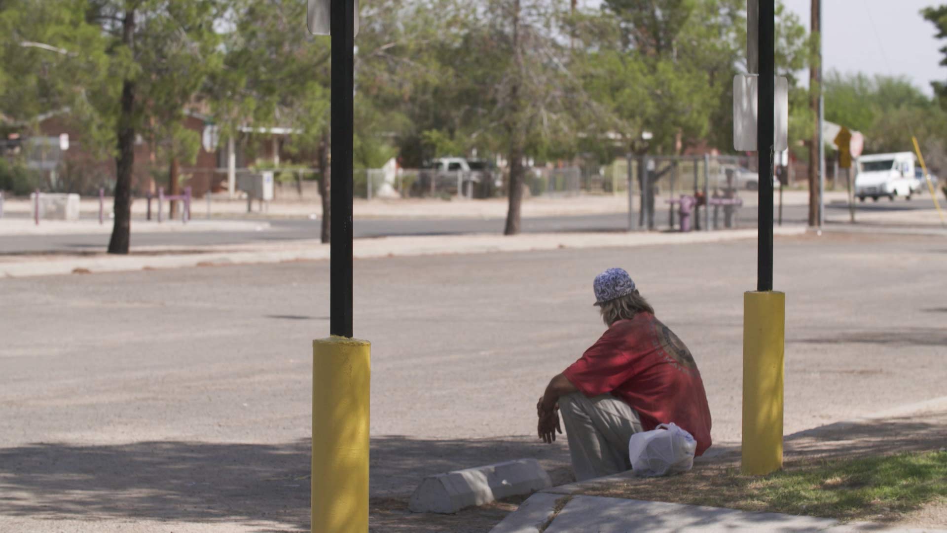 A man sits on the curb at Santa Rita Park in Tucson.