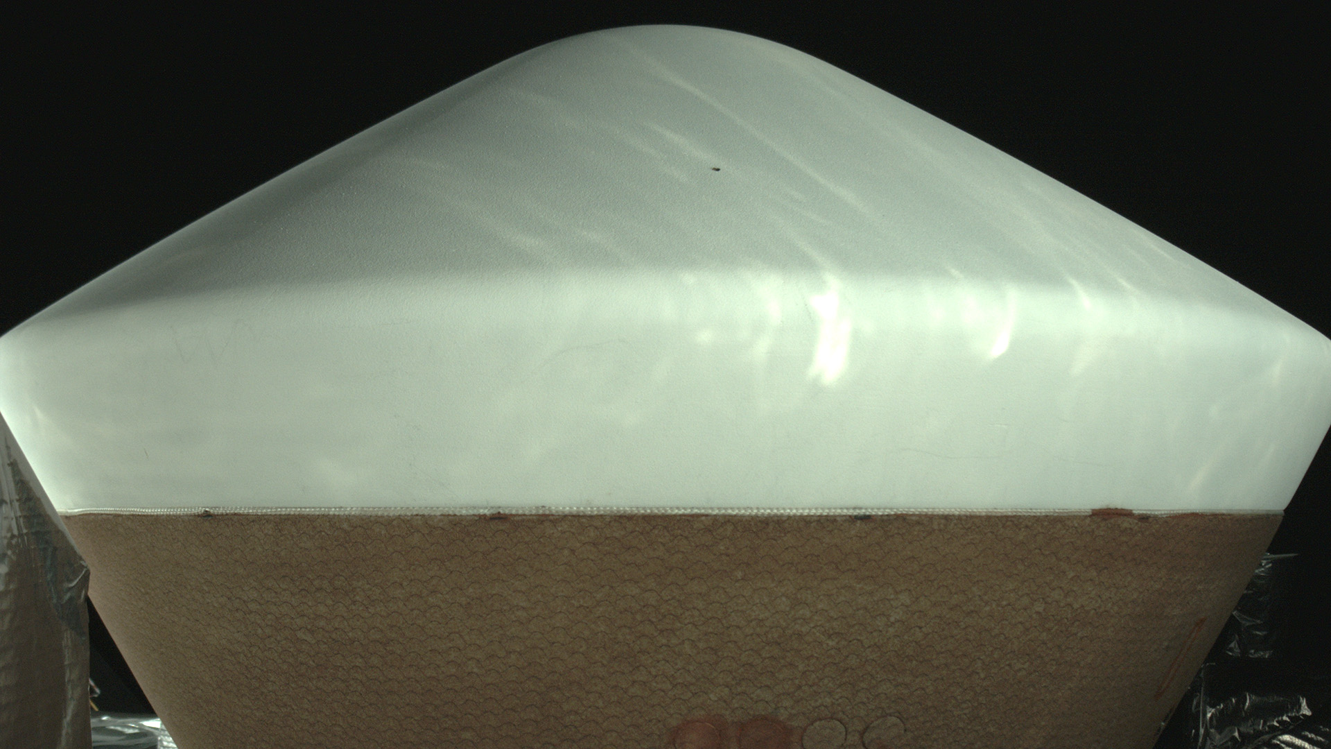A poppy-seed-sized dent (the black spot near the top) was discovered on the heat shield of the OSIRIS-REx sample-return capsule in an image taken by an on-board camera March 2, 2017. The damage won't affect the capsule's performance.