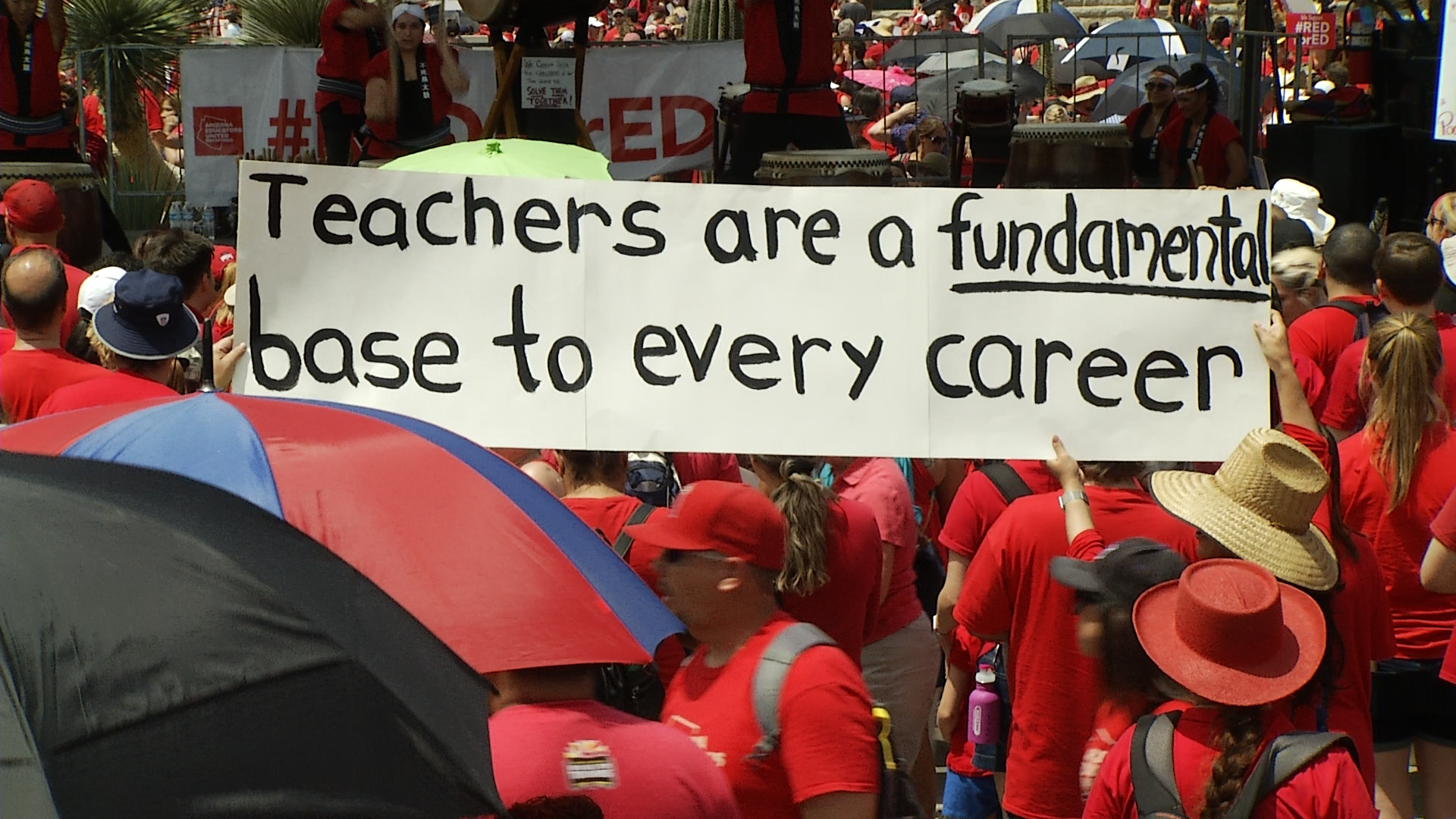 Demonstrators with the Red for Ed movement hold a banner supporting educators outside of the Capitol in Phoenix.