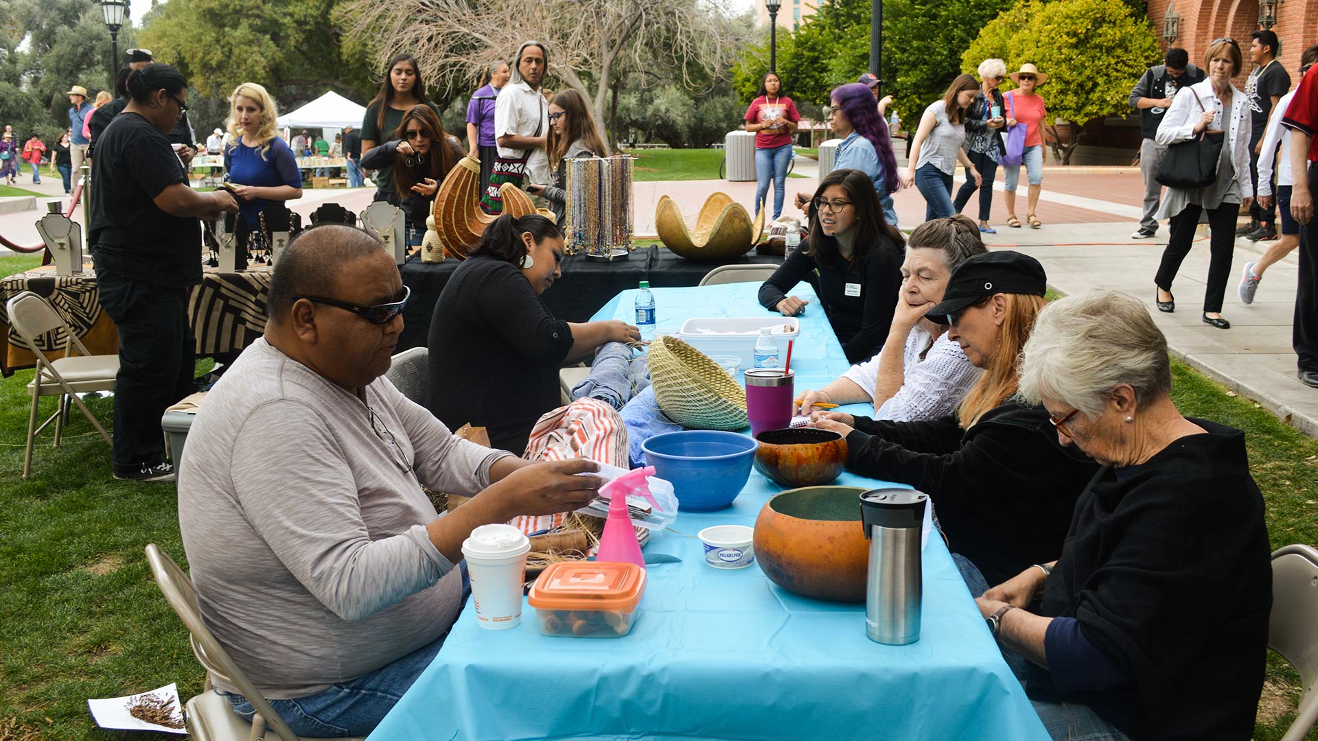 Tohono O'odham basket weaver Terrol Dew Johnson, seated left, gives a workshop outside the Arizona State Museum. Johnson is one of the master artists who participated in the museum's series. 