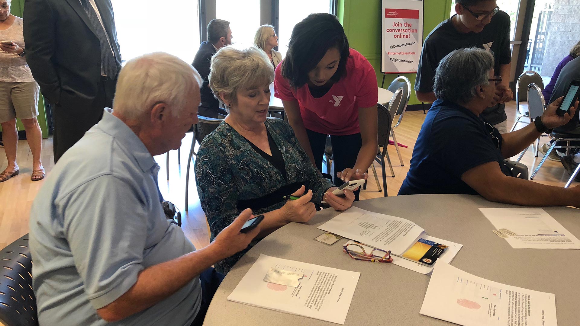 Joy Mona, 19, teaches two seniors how to navigate their iPhones at a pilot Teeniors workshop at the Northwest YMCA in Tucson. 