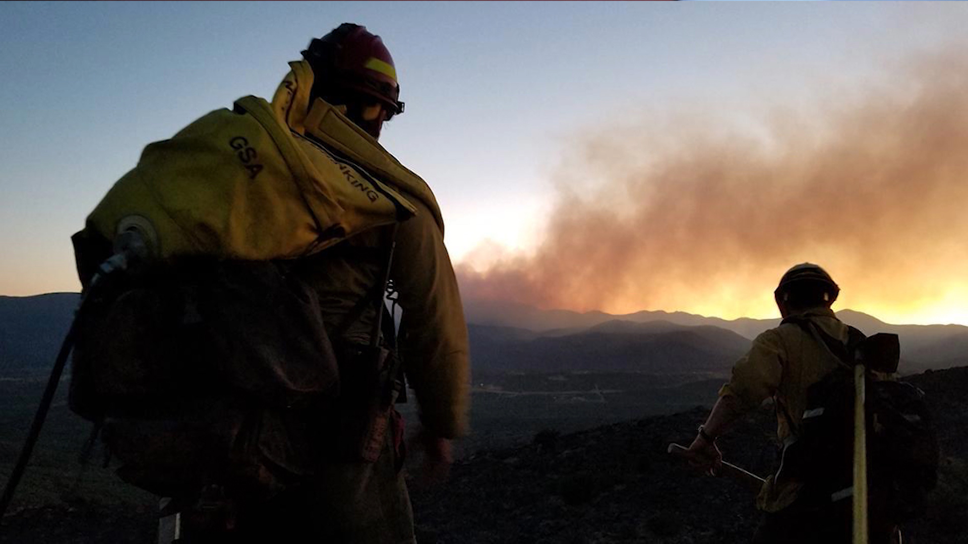 Wildland firefighters watch smoke from a wildfire.