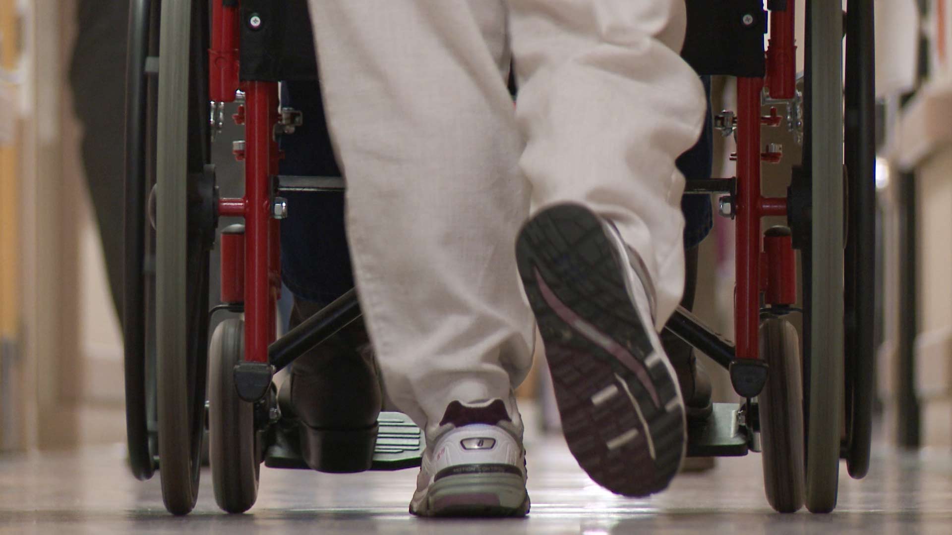 A nurse pushes a patient in a wheelchair.