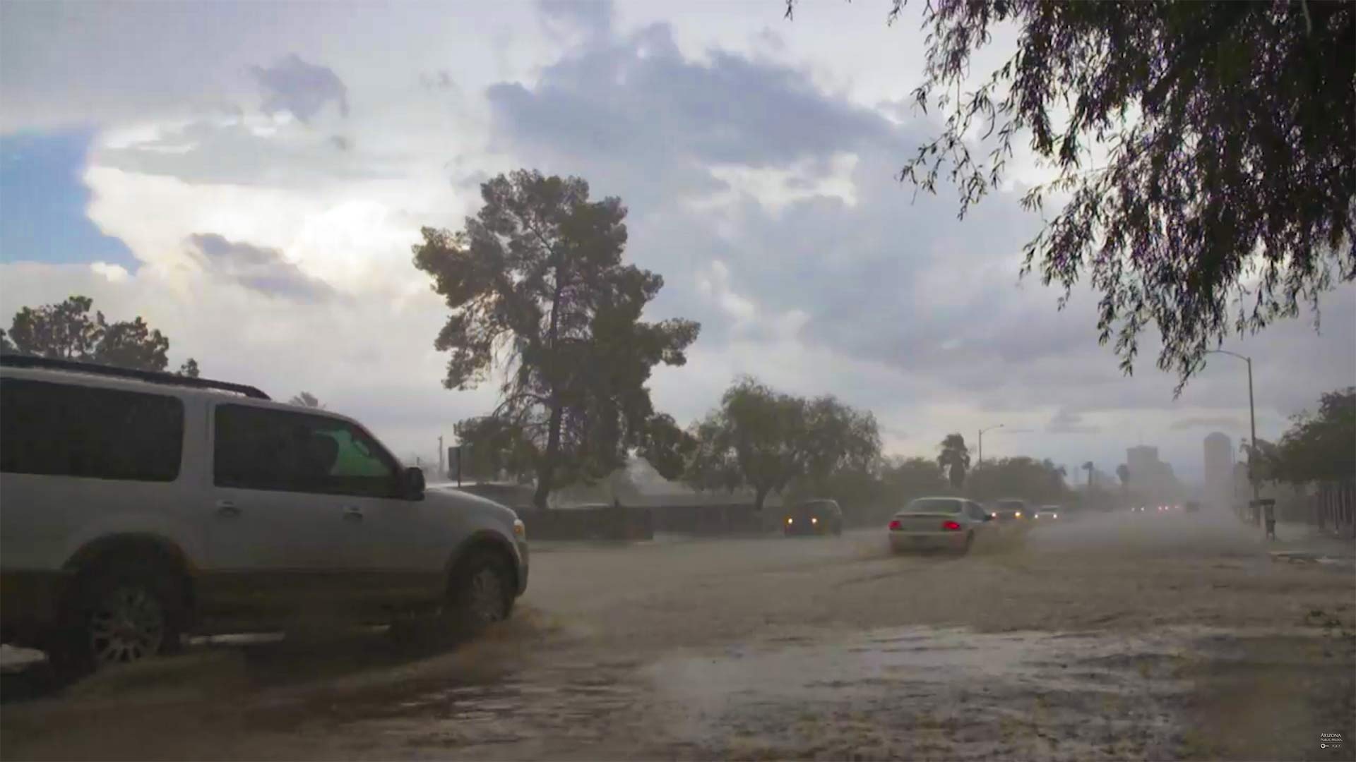 Cars drive through Tucson streets flooding with monsoon rains.