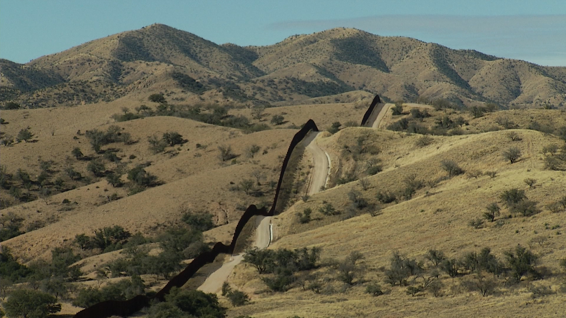 The border fence passes over hills on the line between Arizona and Mexico.