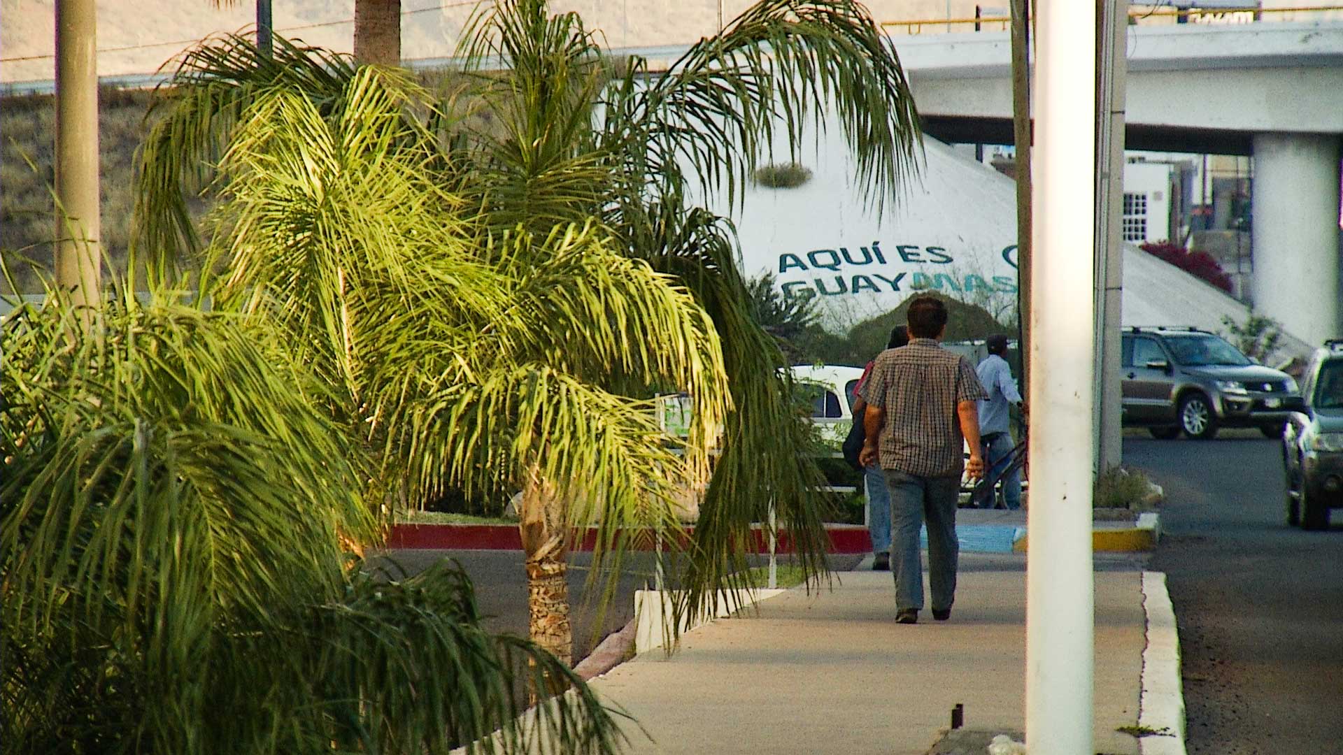 Cars pass as pedestrians walk down a sidewalk in Guaymas, Sonora, March 2017.