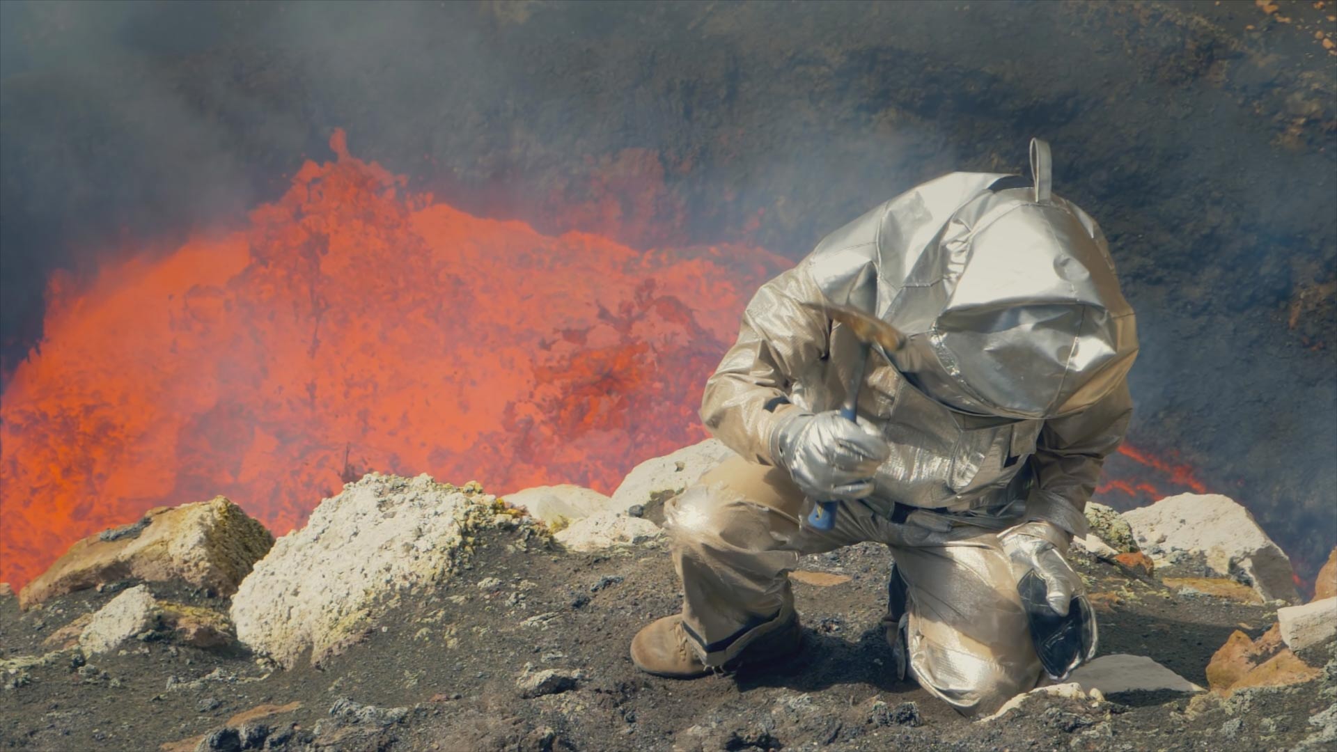 Scientist Dr. Jeffrey Marlow takes samples with the bubbling lava lake of Marum, Vanuatu behind him.